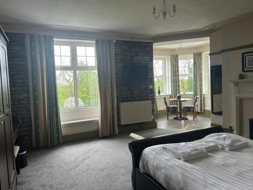 a bedroom with a bed and a table and windows at Broadway Country House in Laugharne