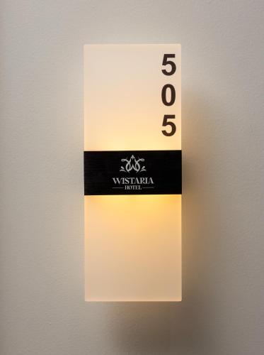 a white and black sign on a wall at Cat Ba Wistaria Hotel- Jacuzzi Rooftop & Fitness in Cat Ba