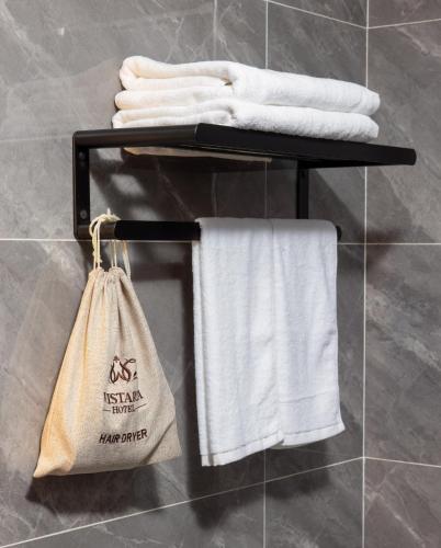 a towel rack with white towels and a bag at Cat Ba Wistaria Hotel- Jacuzzi Rooftop & Fitness in Cat Ba