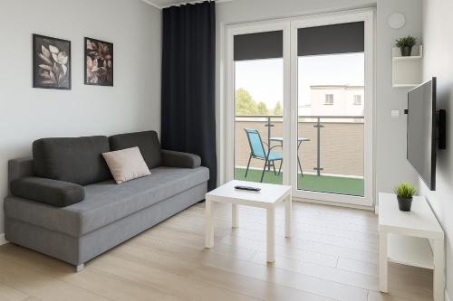 un salon avec un canapé et une table dans l'établissement Urban Jungle - Silver Apartment, à Białystok