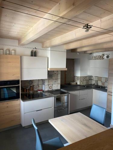 a kitchen with white cabinets and a table and blue chairs at tabià piz meda in Moena