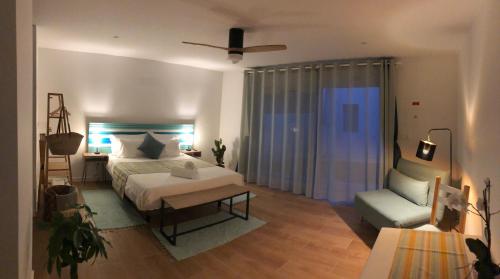 a bedroom with a bed and a couch and a chair at Nareia in Vila Nova de Milfontes
