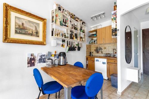 une cuisine avec une table en bois et des chaises bleues dans l'établissement Superbe T2 avec jardin, clim à 600m de la plage, à Carqueiranne