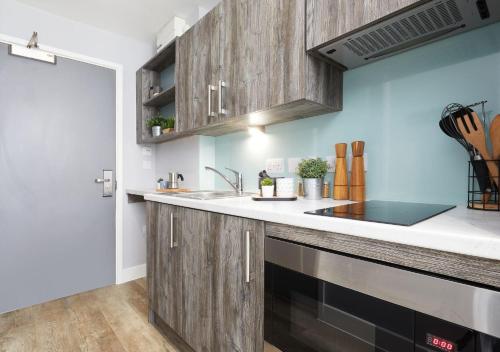 a kitchen with wooden cabinets and a sink at For Students Only - Collegiate Crown Place Cardiff in Cardiff