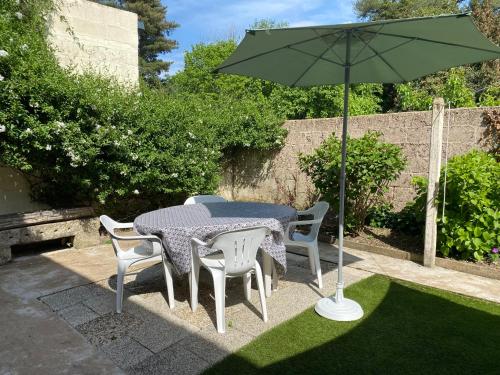 - une table et des chaises avec un parasol dans la cour dans l'établissement Maison de ville avec jardin, à Malestroit