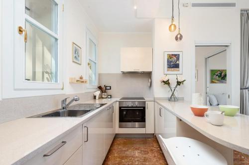 une cuisine blanche avec un évier et un comptoir dans l'établissement MAISON GARAVAN - Somptueux 2 pièces - Vue Mer - Menton, à Menton