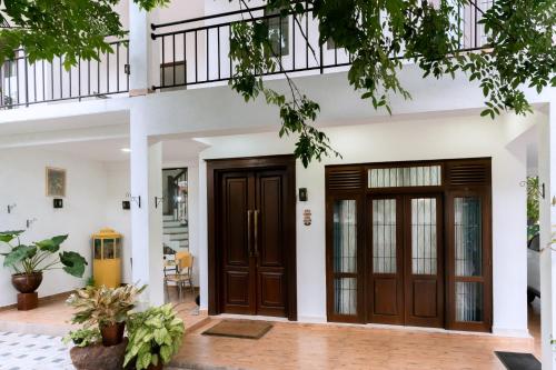 a house with two wooden doors in front of it at Villa Wings Airport Transit in Andiambalama