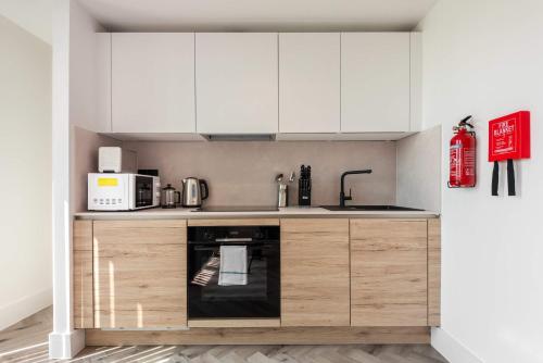 a kitchen with white cabinets and a black oven at Stunning 1 Bedroom Apartment in Central Sheffield in Sheffield