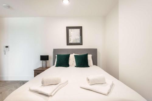 a white bedroom with a large bed with green pillows at Stunning 1 Bedroom Apartment in Central Sheffield in Sheffield
