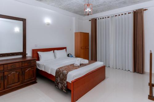 a bedroom with a bed and a dresser and a television at Villa Wings Airport Transit in Andiambalama