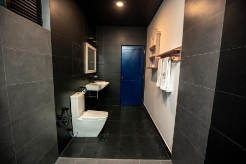 a bathroom with a toilet and a sink and a blue door at Villa Tea Escape in Mahingala