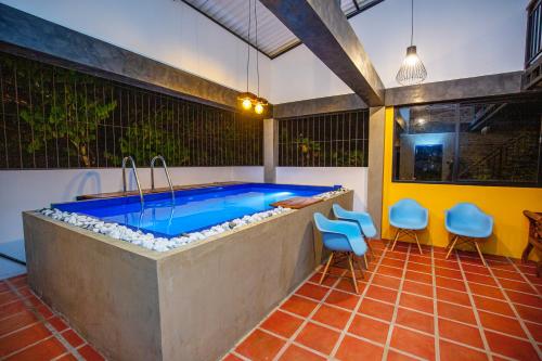 a swimming pool with blue chairs in a room at Villa Tea Escape in Mahingala