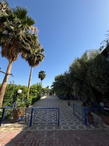 a cobblestone street with palm trees and a gate at Eco Farm Tayssir Marrakech in Marrakech