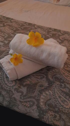 two yellow flowers on a white towel on a bed at Olive Green Villa in Negombo for Airport Transit in Katunayaka