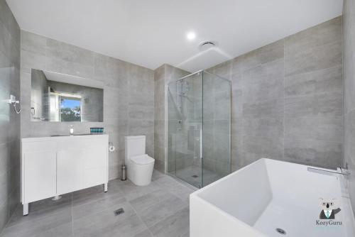 a bathroom with a tub and a shower and a toilet at KozyGuru | Wentworthville | 2 Bed 2 Bath Apt in Wentworthville