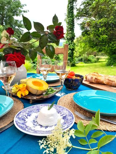 une table bleue avec des assiettes de nourriture et des verres à vin dans l'établissement Moulin Caro, à Rosnoën