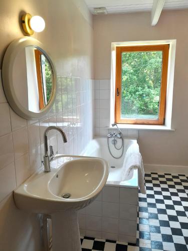 une salle de bain avec un lavabo, un miroir et une baignoire dans l'établissement Moulin Caro, à Rosnoën