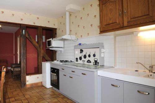 une cuisine blanche avec une cuisinière et un évier dans l'établissement Le saint martin, à Saint-Rémy-sous-Barbuise