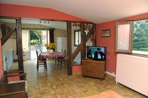 un salon avec une télévision et une table avec des chaises dans l'établissement Le saint martin, à Saint-Rémy-sous-Barbuise