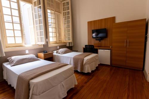 ein Hotelzimmer mit zwei Betten und einem Flachbildfernseher in der Unterkunft Hotel Municipal Araraquara in Araraquara