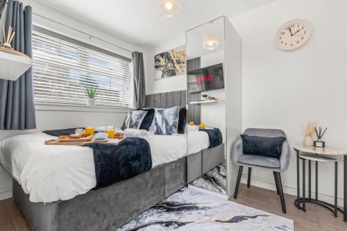 a bedroom with a bed and a chair and a clock at La Maisón, City Centre House, EV Parking, Fast WiFi, Netflix Private Entrance, Garden in Coventry