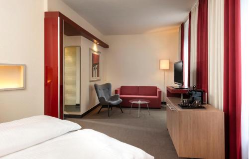 a hotel room with a bed and a red couch at Mövenpick Hotel Münster am Aasee in Münster