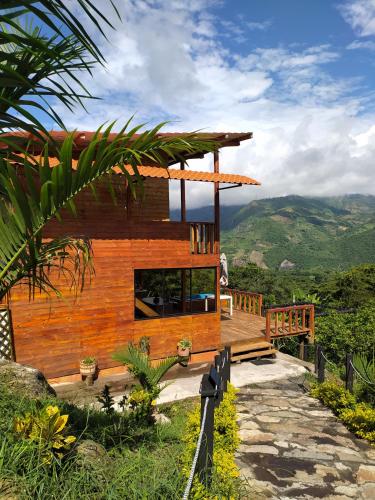 a wooden house with a deck and mountains in the background at Cabaña con vistas a la montaña in Cachipay