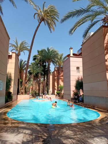 un gruppo di persone in una piscina con palme di RIAD Le shams a Marrakech