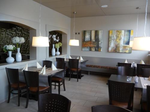 a dining room with tables and chairs and paintings at Hotel Bahnhof in Uzwil