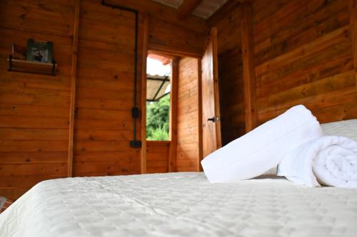 a bedroom with a bed with white sheets and a window at Cabaña con vistas a la montaña in Cachipay