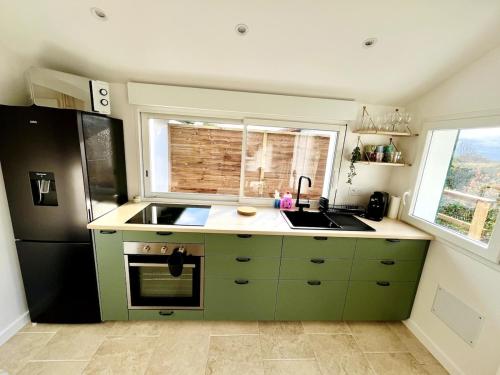 - une cuisine avec des placards verts et un réfrigérateur noir dans l'établissement Maison cosy entre océan et montagne, à Hasparren