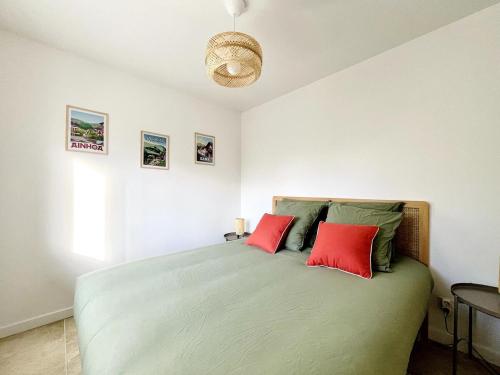 une chambre avec un lit avec deux oreillers rouges dans l'établissement Maison cosy entre océan et montagne, à Hasparren