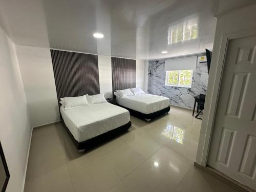 a bedroom with two beds and a window and a door at Apartahotel Plaza in San Andrés