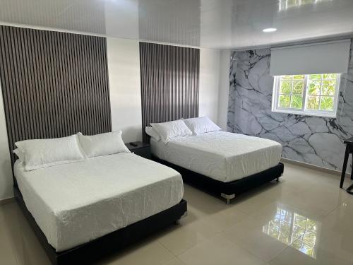 a bedroom with two beds and a window at Apartahotel Plaza in San Andrés