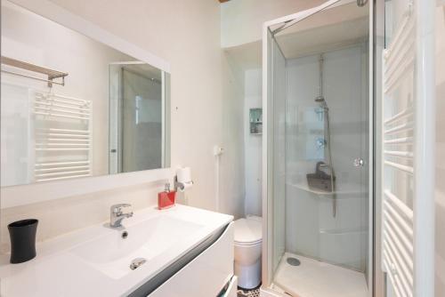 une salle de bain blanche avec un lavabo et une douche dans l'établissement T2 cosy résidence Plein Soleil, à Eaux-Bonnes