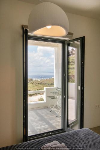 a room with a large window with a view of a balcony at Rockaine Suites Echoes in Tinos