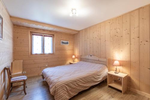 a bedroom with a bed and a chair and a window at Les Laouchets - Chalet 8 pers in Sixt