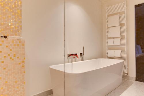 a white bath tub in a bathroom with a shower at Hotel De Witte Lelie -Small Luxury Hotels of the World in Antwerp