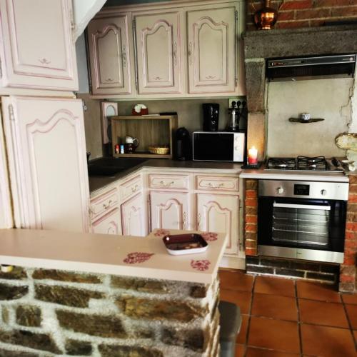 une cuisine avec des armoires blanches et un four à plaques de cuisson dans l'établissement Chez Nicole et Patrick, à Chouvigny