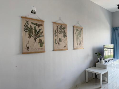 three paintings on a white wall with a table at The Horizon - Ipoh' Rachel in Ipoh