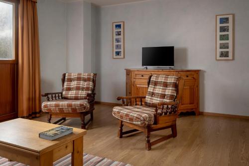 a living room with two chairs and a flat screen tv at Chalet Stelle Di Neve in Bormio