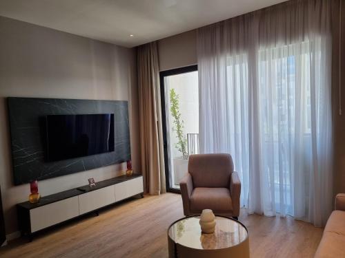 ティヴァトにあるBOKA PLACE One Bedroom Apartment NEWのテレビと椅子とテーブルのあるリビングルーム