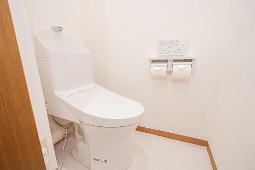 a white toilet in a bathroom with a clock on the wall at Shinjuku Terrace 226 BnB in Tokyo