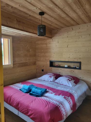 łóżko w pokoju z drewnianymi ścianami w obiekcie Appartement cosy face aux Aravis w mieście Le Grand-Bornand