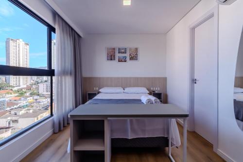 a bedroom with a bed and a large window at Loft Novo todo Mobiliado com WIFI Piscina e próximo a Oktober in Blumenau