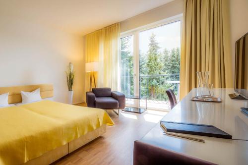 Cette chambre comprend un lit jaune et un bureau. dans l'établissement Midori - The Green Guesthouse, à Dossenheim