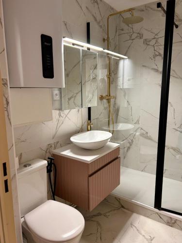 une salle de bain avec un lavabo, des toilettes et une baignoire dans l'établissement Votre évasion au bord de mer, à Courseulles-sur-Mer