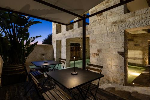 a patio with two tables and a stone wall at Amalen Suites Adults Only in Rethymno Town