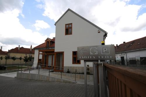 a white house with a sign in front of it at Gizella Hotel and Restaurant in Veszprém