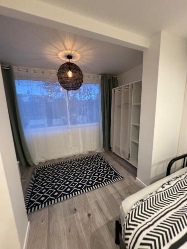 une chambre avec un lit, une fenêtre et un lustre dans l'établissement Studio au calme - Villeneuve Loubet, à Villeneuve-Loubet